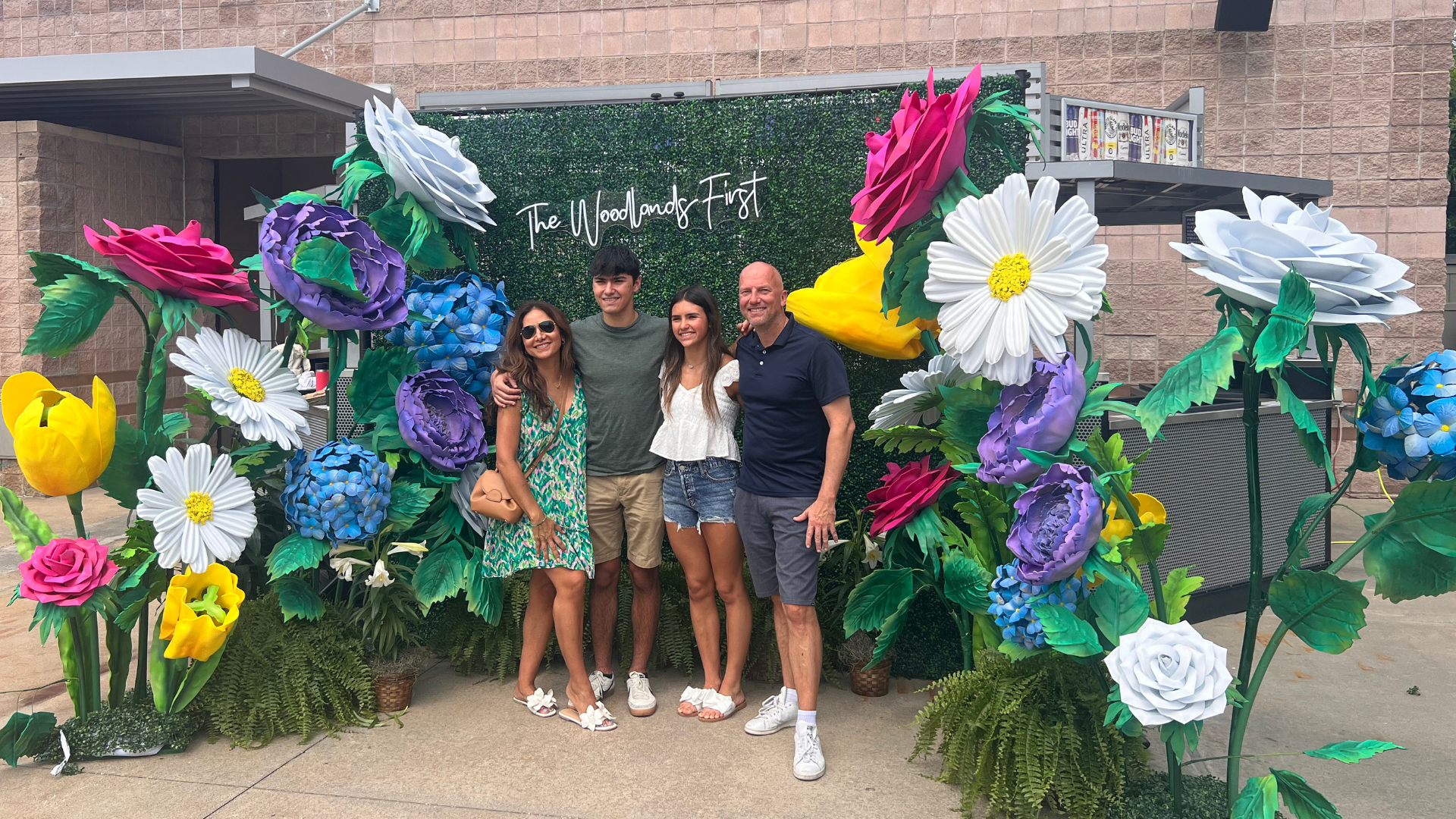 Photo Area Selfie Station with Giant Flowers and Boxwood backdrop with a family taking a picture